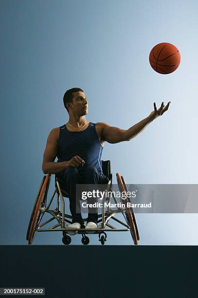 paraplegic male athlete throwing basketball in air - baloncesto en silla de ruedas fotografías e imágenes de stock