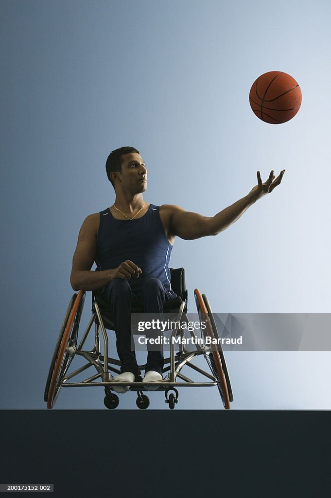 Paraplegic male athlete throwing basketball in air