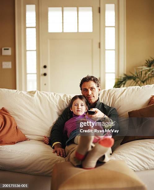 father and daughter (4-6) sitting on couch, watching tv - guardare la tv foto e immagini stock