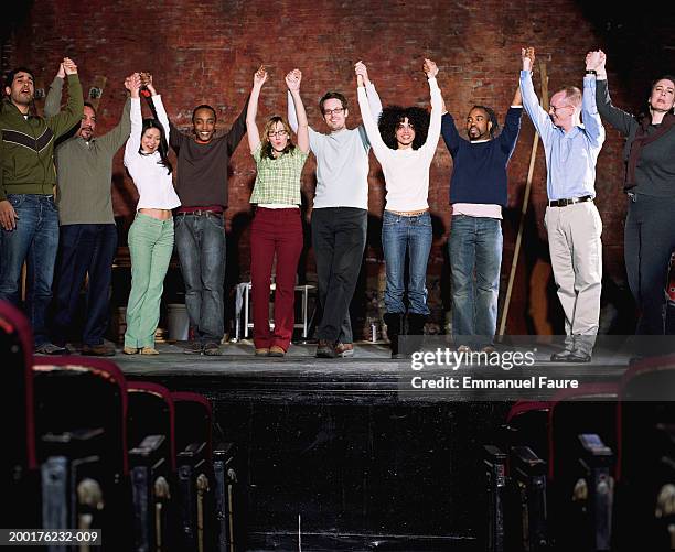 group of people on stage in theater holding hands up in air, smiling - actor stock pictures, royalty-free photos & images