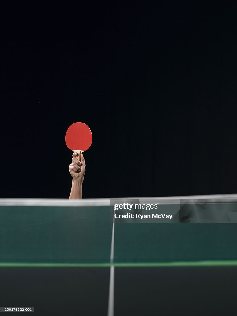 Man holding table tennis paddle above table
