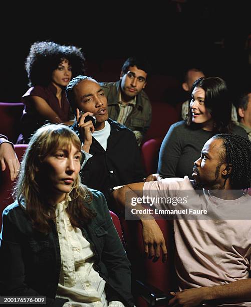 group of people in movie theater, man using mobile phone - mancanza di rispetto foto e immagini stock