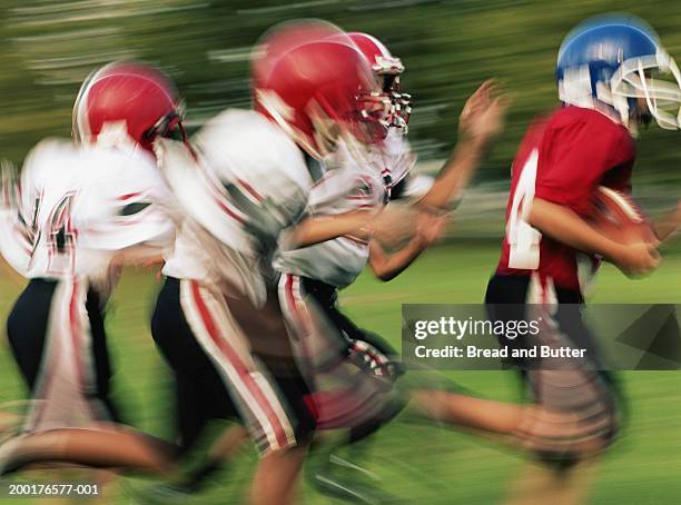 boys (8-10) playing in football game, side view (blurred motion) - rush american football stockfoto's en -beelden