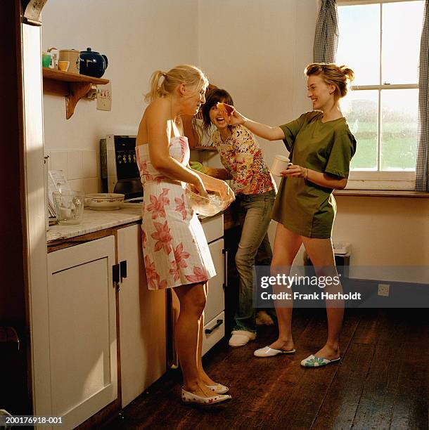 three young women in kitchen, laughing - young women group back stock-fotos und bilder