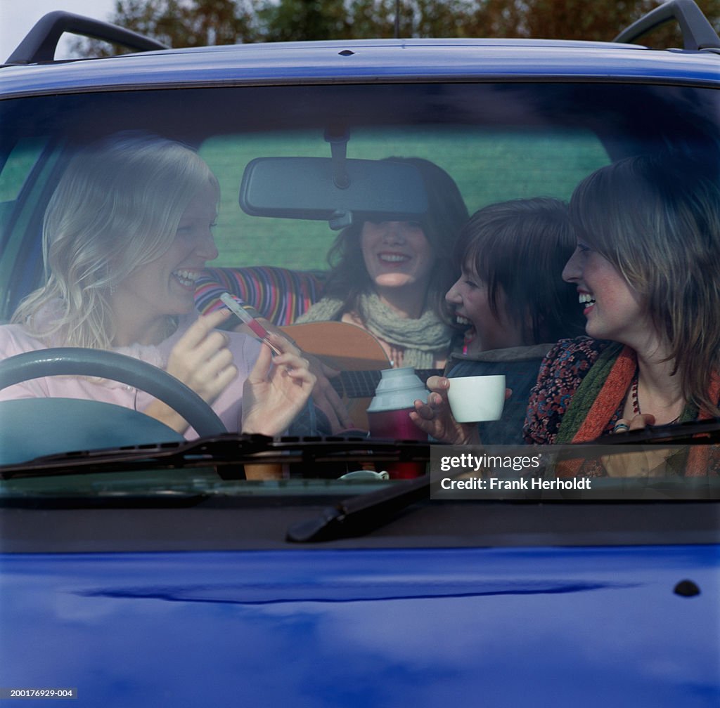 Four young women in car, laughing, view through front window