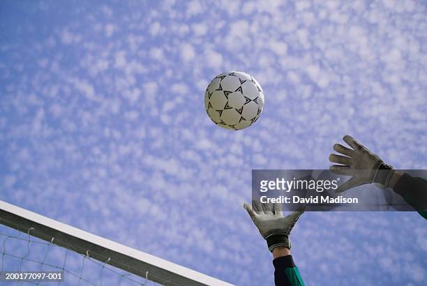 male soccer goalie reaching for ball, low angle view - goalkeeper gloves stock pictures, royalty-free photos & images