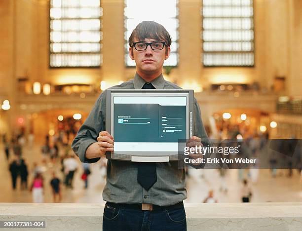 man holding up computer monitor in train station, portrait - geek stock-fotos und bilder