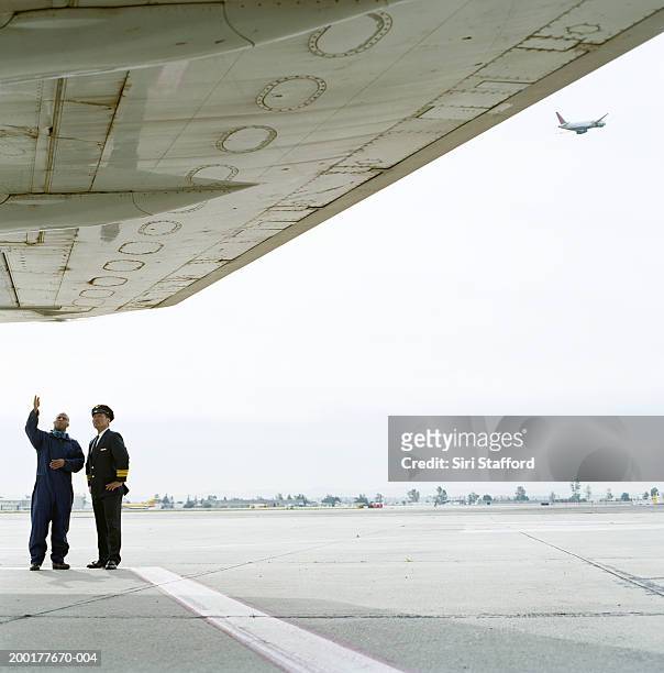 airport ground technician inspecting plane with pilot - airline pilot imagens e fotografias de stock