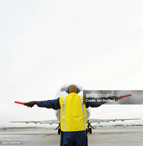 airport ground crew directing aircraft, rear view - airport ground crew stock pictures, royalty-free photos & images