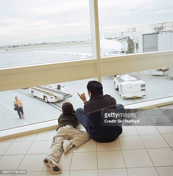 father and son (6-8)looking outside window of airport lounge - voyage15 photos et images de collection