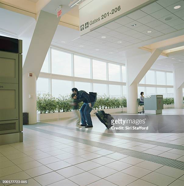 boy (6-8) running to welcome father in airport - voyage15 photos et images de collection