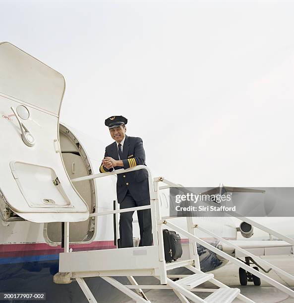 pilot leaning on railing of aircraft stairs, portrait - commercieel vliegtuig deur stockfoto's en -beelden