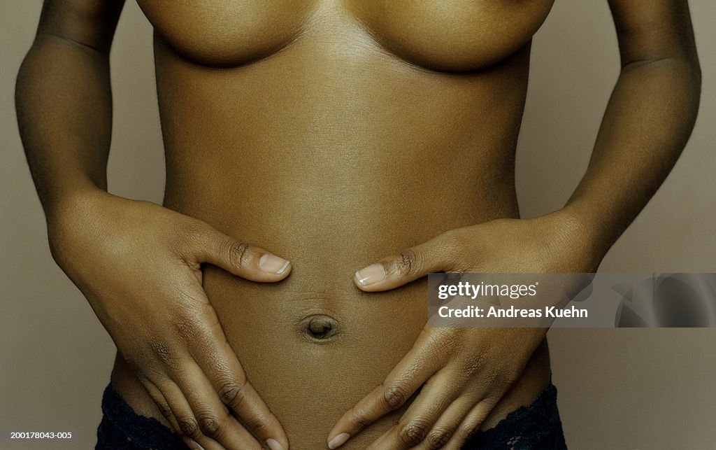 Semi-dressed woman, hands on stomach, mid section