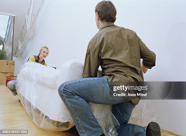 mature couple lifting covered sofa - laminat stock-fotos und bilder