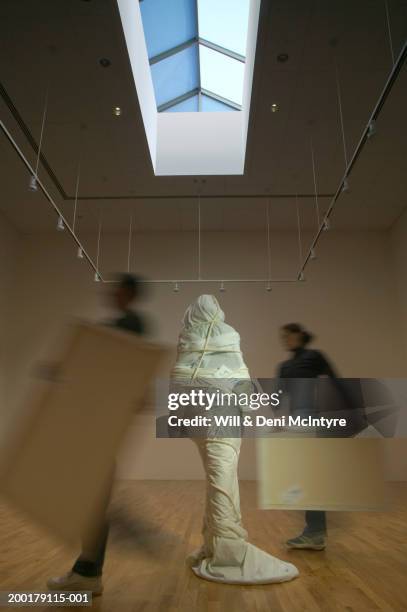 man and woman moving art into gallery (blurred motion) - skulptur kunstwerk stock-fotos und bilder