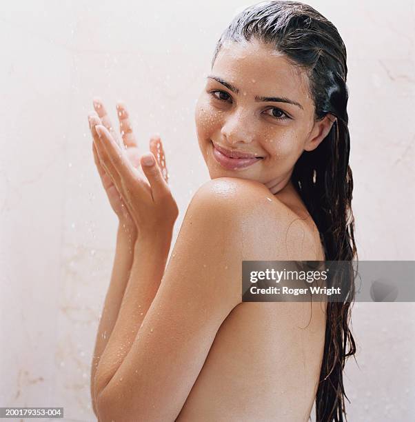 young woman under shower, smiling, portrait - women shower stock-fotos und bilder