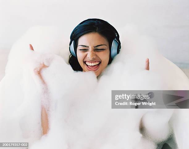 young woman in bubble bath wearing headphones, singing - woman bath bubbles stock-fotos und bilder