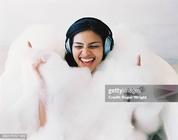 young woman in bubble bath wearing headphones, singing - bubblebath stock pictures, royalty-free photos & images