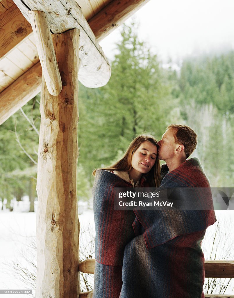 Junges Paar mit Decke auf Veranda, Mann Küssen