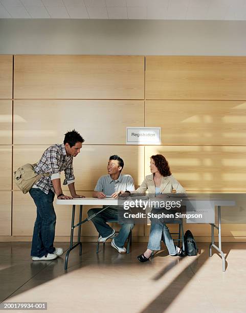 college students at registration table - anmelden stock-fotos und bilder