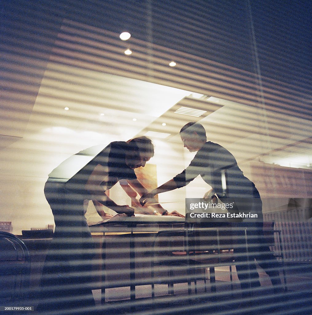 Two colleagues preparing package for mailing in conference room