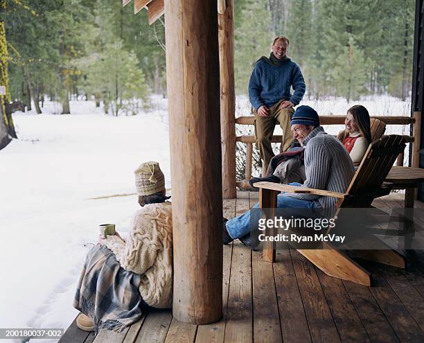 four adults sitting on porch of cabin, laughing, winter - cabin fotografías e imágenes de stock