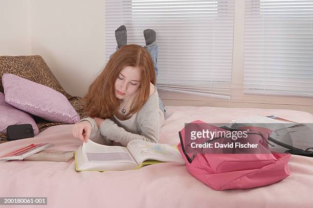 teenage girl (13-15) laying on bed, reading book - teen packing suitcase stock pictures, royalty-free photos & images