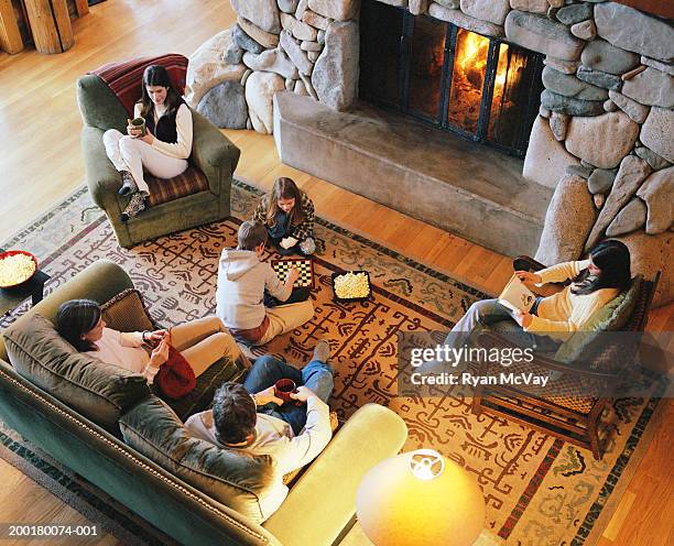 parents and children (7-16) sitting beside fireplace, elevated view - fireplace fotografías e imágenes de stock