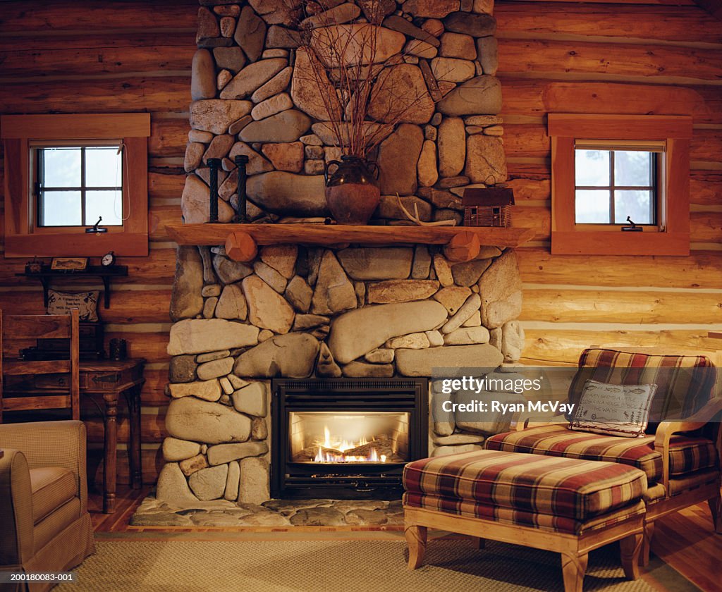 Armchair beside stone fireplace in log cabin