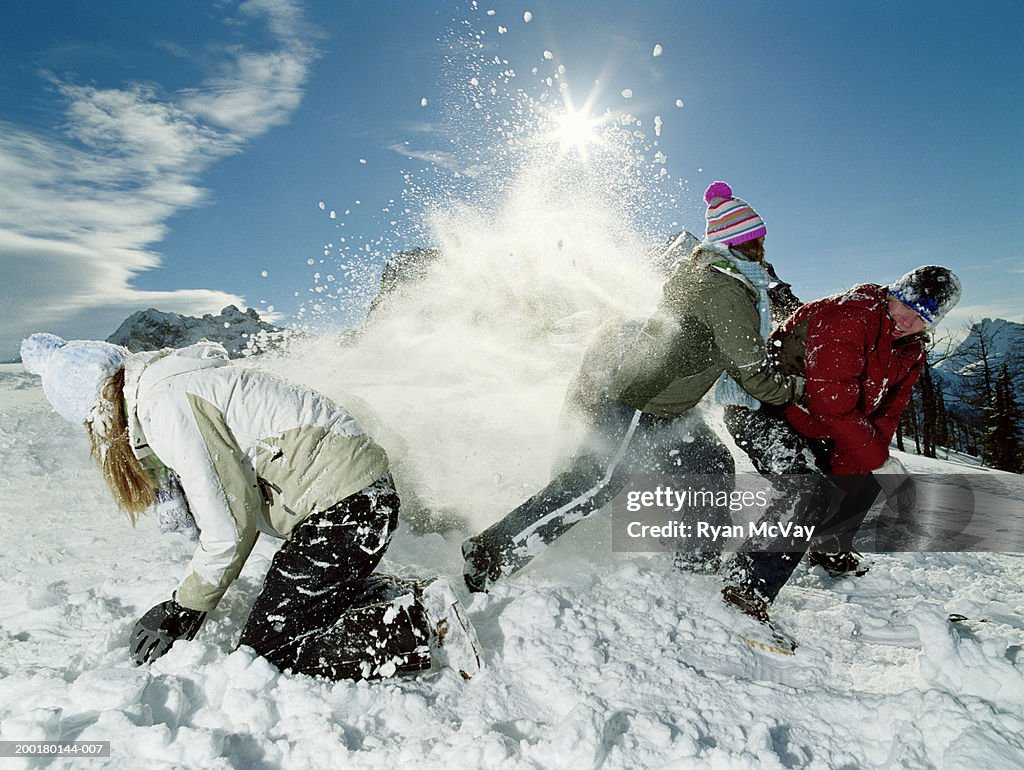 Three teenagers (15-17) roughhousing in snow, side view