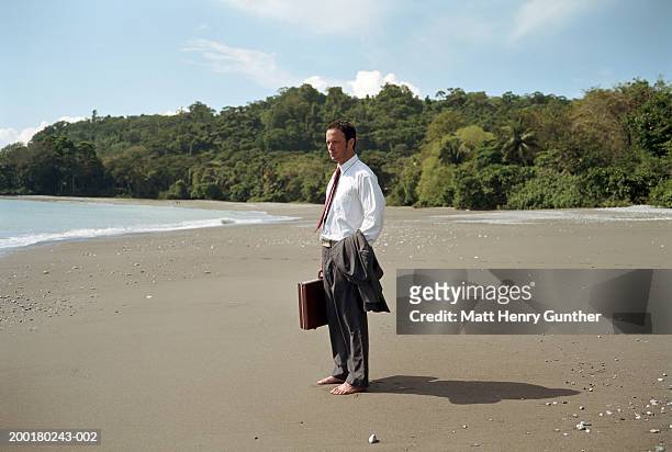 businessman on beach holding surfboard and briefcase, rear view - barefoot men 個照片及圖片檔