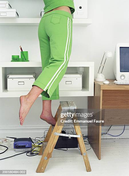 young woman balancing on one foot on step ladder, low section - step ladder stock-fotos und bilder