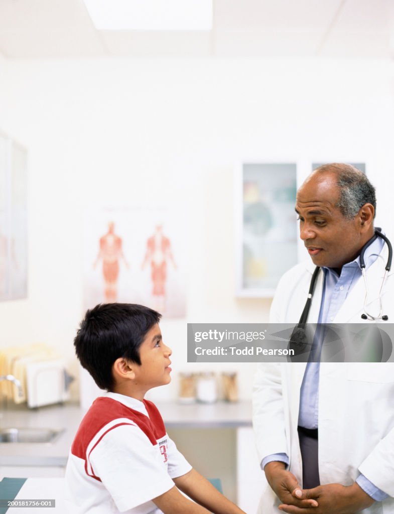 Pediatrician talking to boy (6-8) in examination room, side view