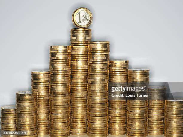 euro currency:  one euro coin balanced on stacked euro coins, close-up - large group of objects stock pictures, royalty-free photos & images
