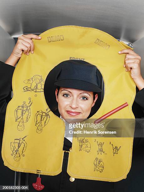 air stewardess demonstrating with deflated life jacket, portrait - life jacket stockfoto's en -beelden