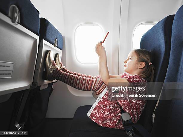 girl (5-7) on aeroplane using handheld electronic device - achterover leunen stockfoto's en -beelden