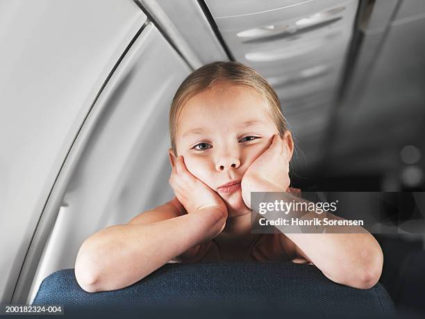 girl (5-7) leaning on back of aeroplane seat, face in hands, portrait - pressure airplane stock pictures, royalty-free photos & images