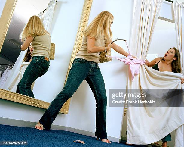 two young women fighting over top in change room of shop - kleidung anprobe stock-fotos und bilder