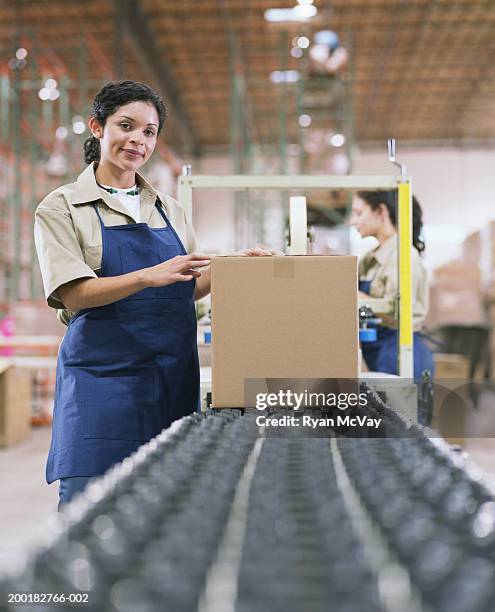 female warehouse worker standing by conveyor belt - boxes conveyor belt stock pictures, royalty-free photos & images