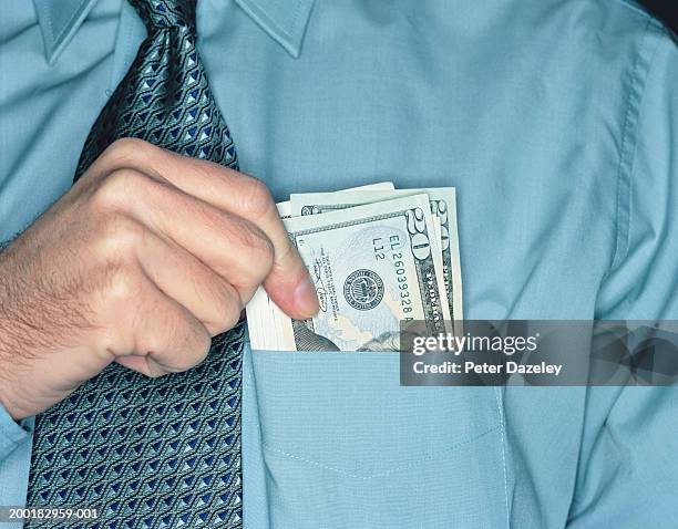 businessman holding twenty dollar notes in shirt pocket, close-up - hands in pockets foto e immagini stock