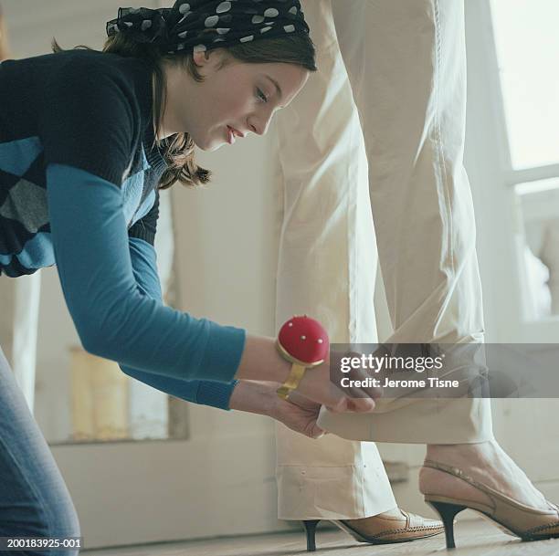 young woman pinning hem on woman's trousers - tailor pants stock pictures, royalty-free photos & images