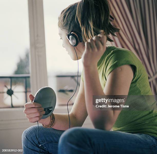 young woman wearing headphones, holding personal cd player - personal compact disc player 個照片及圖片檔