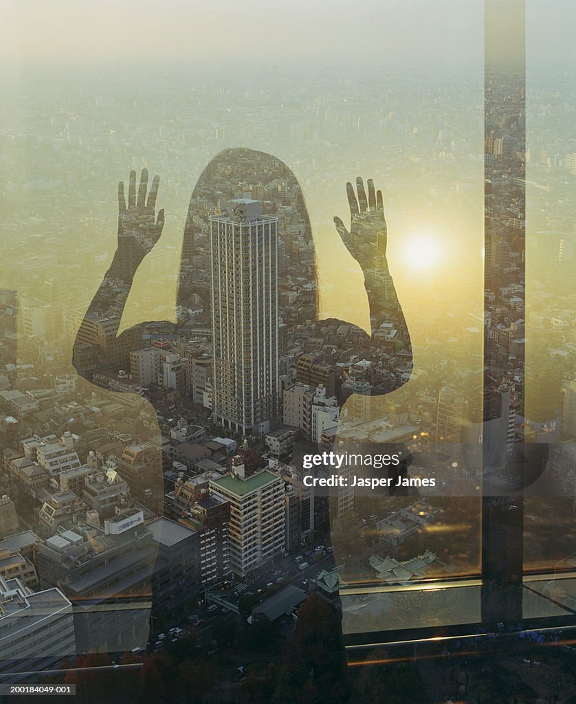 Woman looking out at cityscape, rear view (double exposure)
