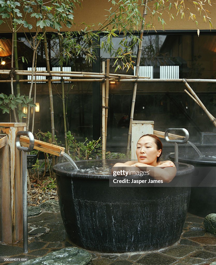 Woman leaning on edge of hot tub, outdoors