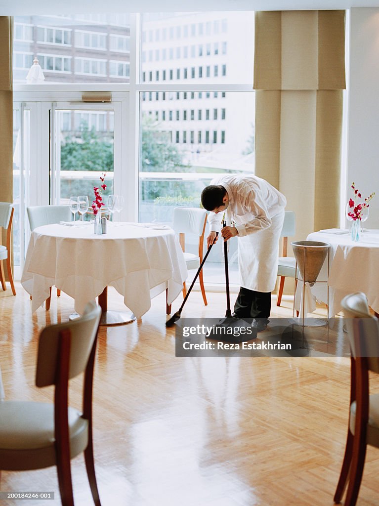 Waiter sweeping restaurant