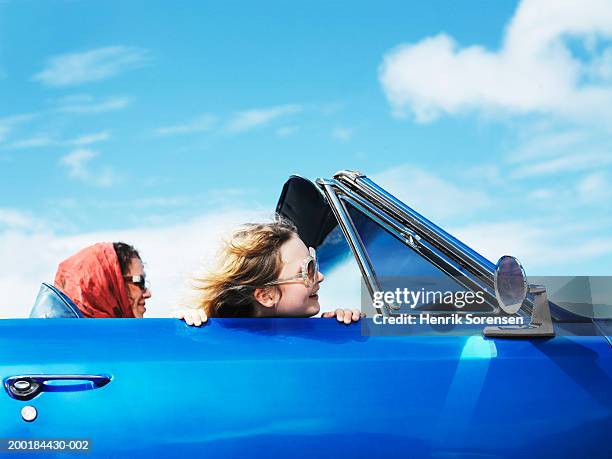 girl (8-10) leaning head over side of convertible car, woman driving - driving car blue stock pictures, royalty-free photos & images