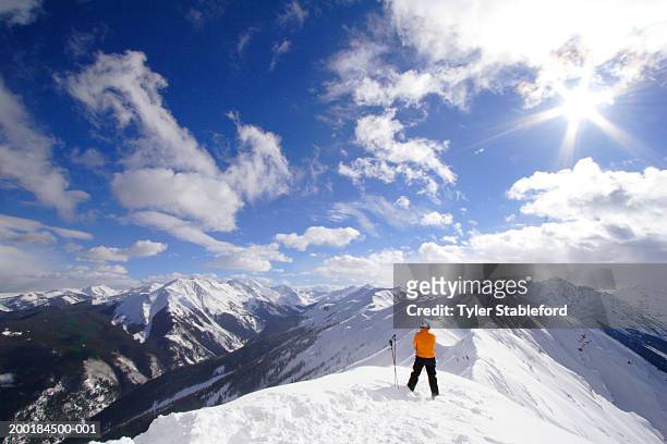 male skier looking at snow covered mountains, rear view - aspen stock-fotos und bilder