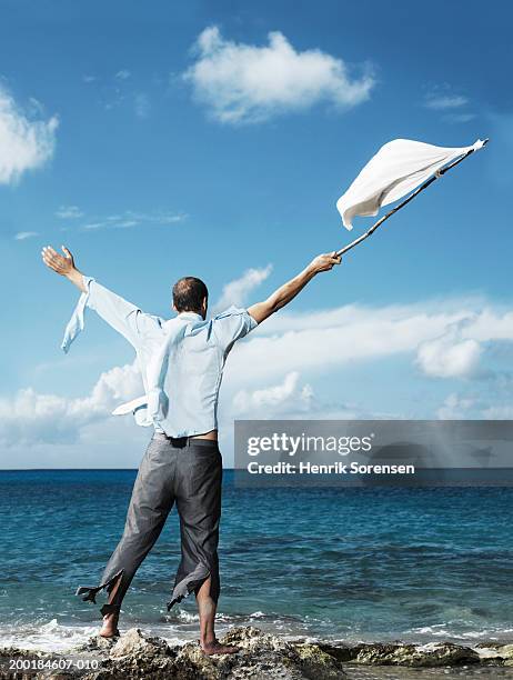 ragged businessman on beach, waving improvised flag, rear view - bandera blanca fotografías e imágenes de stock