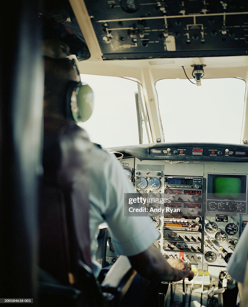 Airplane pilot seated at controls, rear view