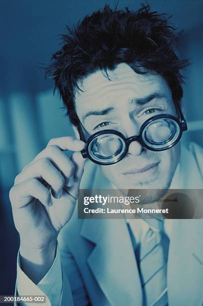 young man peering over goggles, portrait (blue tone) - taking off glasses stock pictures, royalty-free photos & images